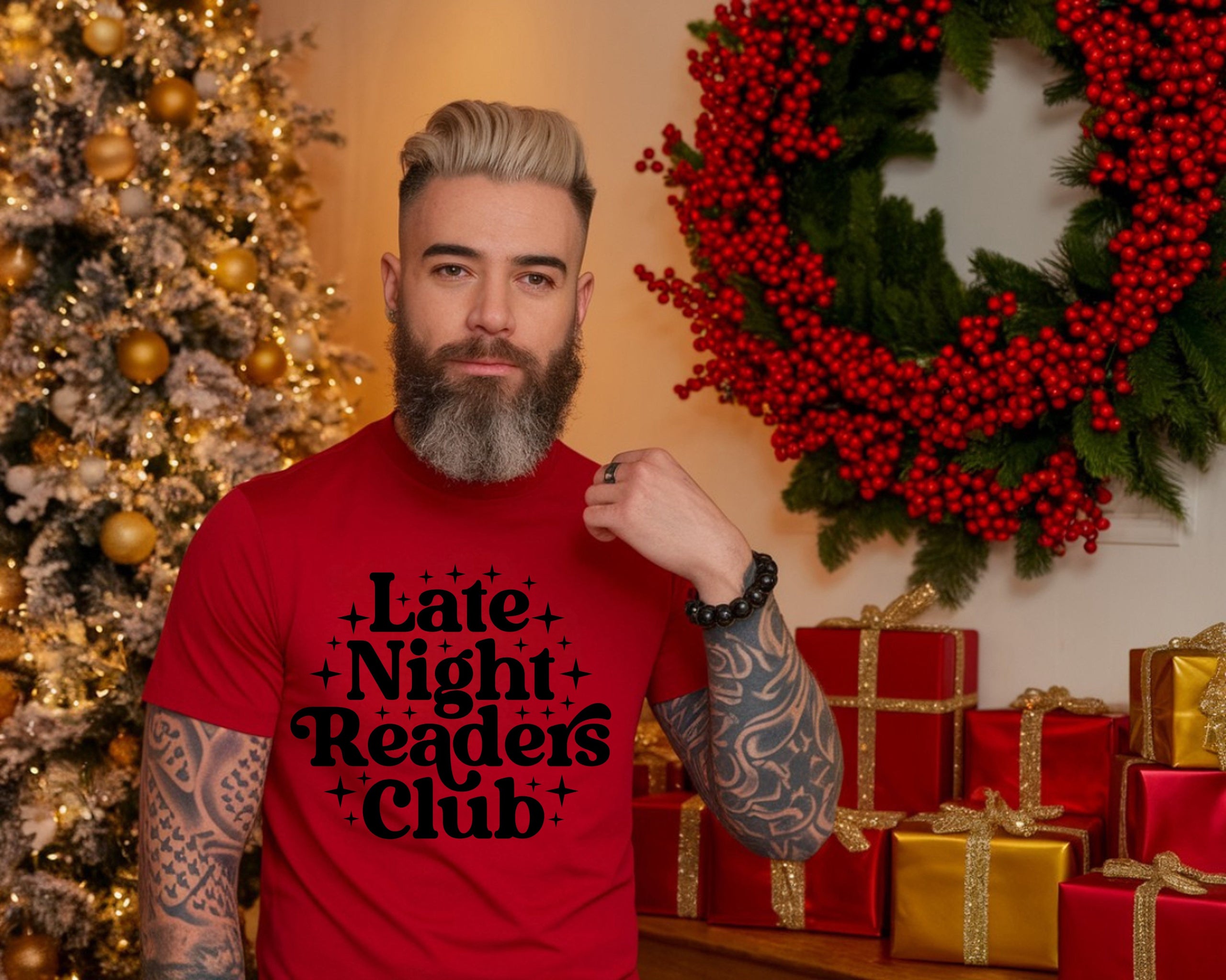 Man wearing a red 'Late Night Readers Club' t-shirt in front of Christmas decorations.