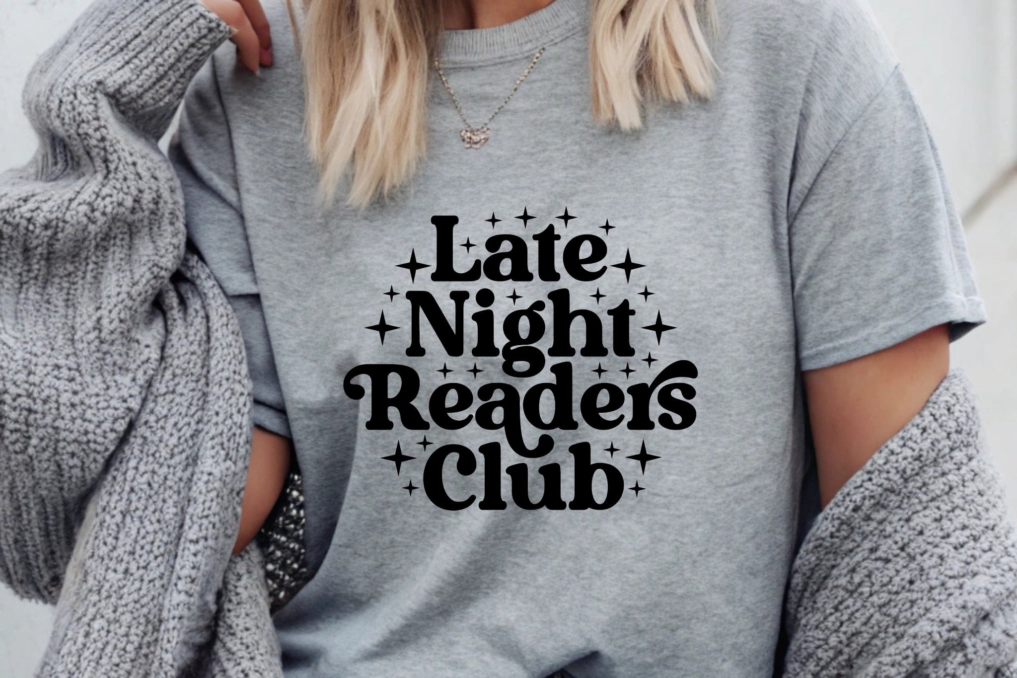 Person wearing a gray t-shirt with 'Late Night Readers Club' text